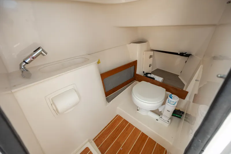 Yacht Photos Pics 2023 Grady-White Freedom 285 boat interior with compact bathroom and wooden flooring.