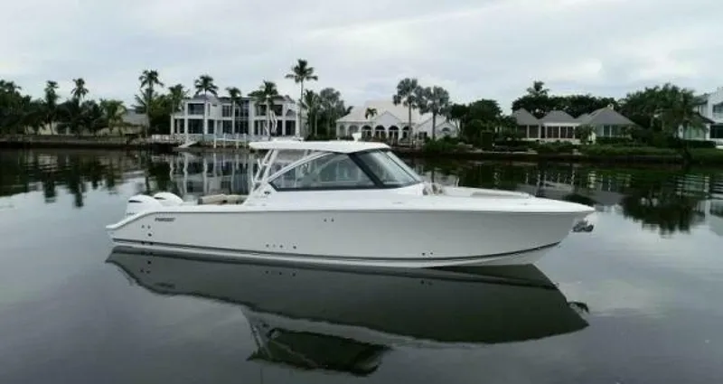  Yacht Photos Pics 2019 Pursuit DC 325 Dual Console boat on calm water, with waterfront homes in the background.