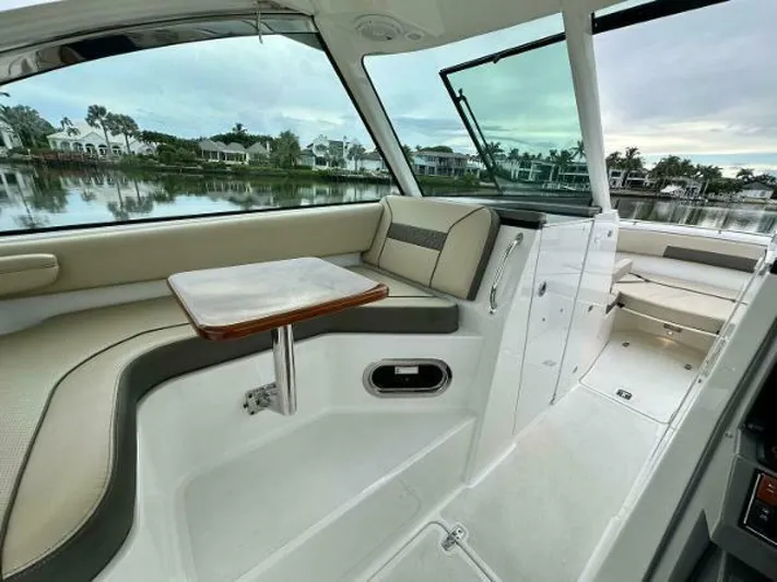  Yacht Photos Pics 2019 Pursuit DC 325 Dual Console interior with seating and table, overlooking waterfront homes.