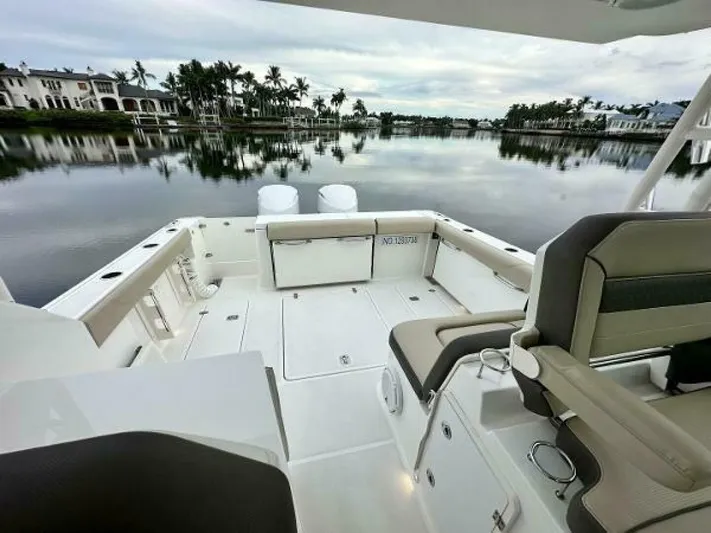  Yacht Photos Pics 2019 Pursuit DC 325 Dual Console boat on calm water, luxurious seating, scenic waterfront view.