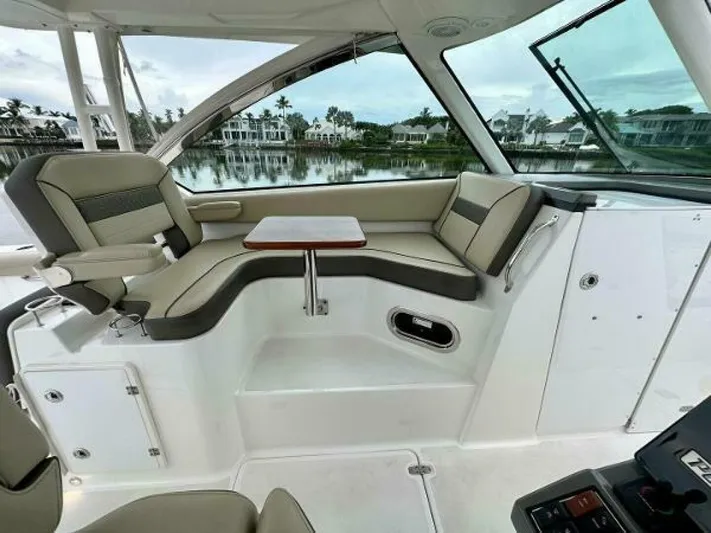  Yacht Photos Pics 2019 Pursuit DC 325 Dual Console boat interior with seating and table, overlooking waterfront homes.