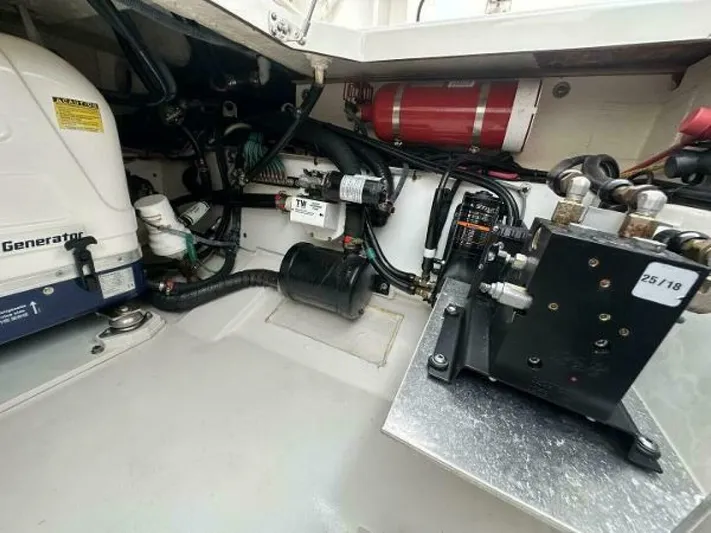  Yacht Photos Pics Engine compartment of a 2019 Pursuit DC 325 Dual Console boat, featuring mechanical components and fire extinguisher.