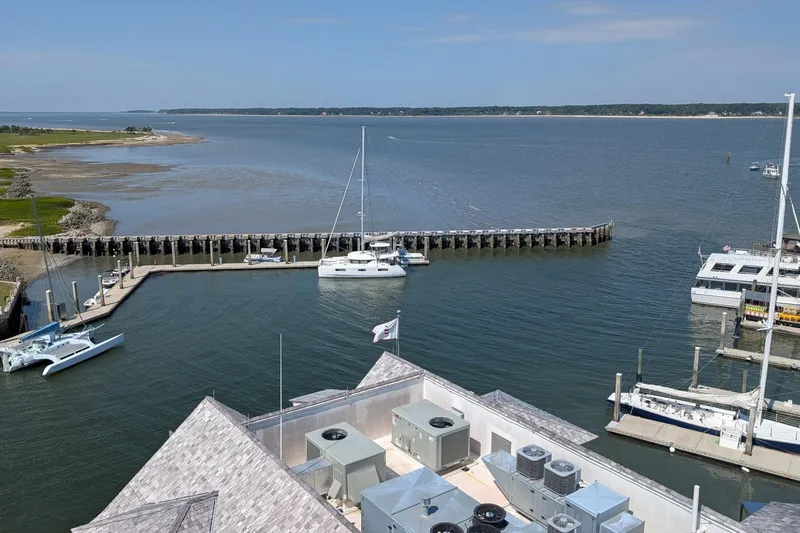 Exodus Yacht Photos Pics Aerial view of a marina with a 2022 Lagoon 46 catamaran docked, surrounded by calm waters.