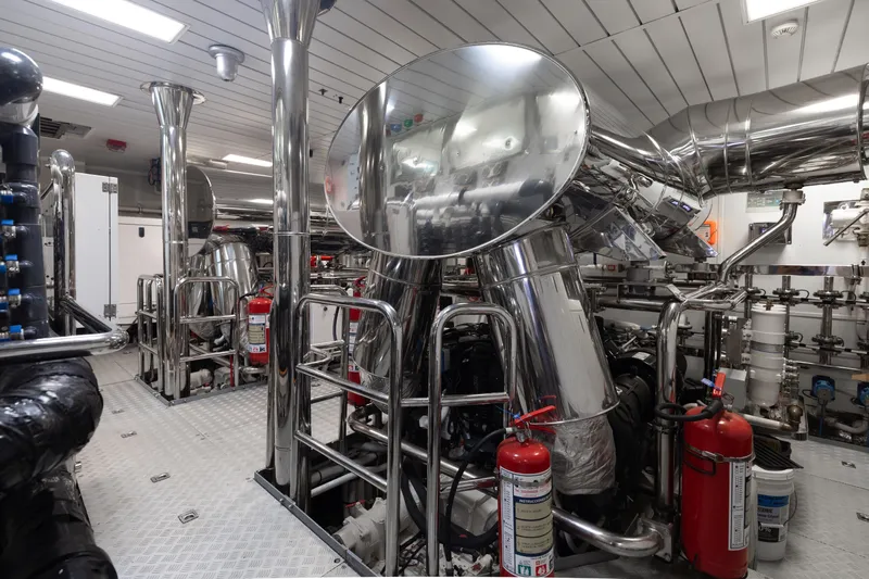 Domani Yacht Photos Pics Engine room of 2016 Benetti Custom Built yacht with polished metal pipes and fire extinguishers.
