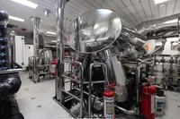 Engine room of 2016 Benetti Custom Built yacht with polished metal pipes and fire extinguishers.
