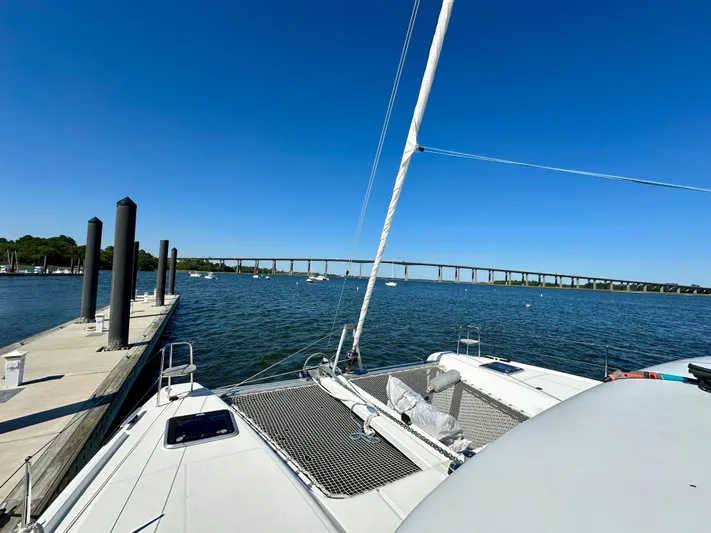 Never Say Never Yacht Photos Pics 2017 Lagoon 42 catamaran docked by a scenic waterfront with a bridge in the background.