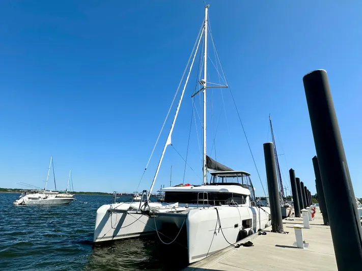 Never Say Never Yacht Photos Pics 2017 Lagoon 42 catamaran docked at a marina under clear blue skies.