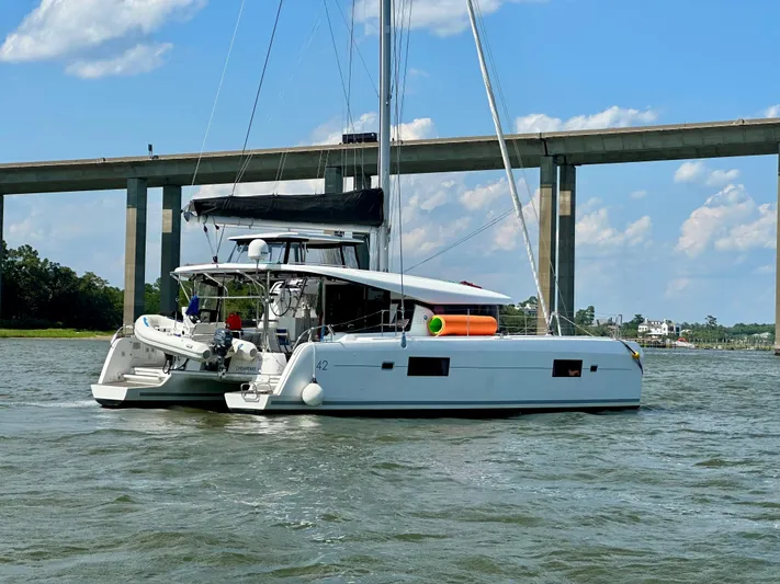 Never Say Never Yacht Photos Pics 2017 Lagoon 42 catamaran sailing near a bridge on a sunny day.