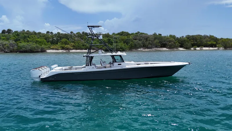  Yacht Photos Pics 2019 HCB 53 Sueños boat on clear blue water near a lush shoreline.