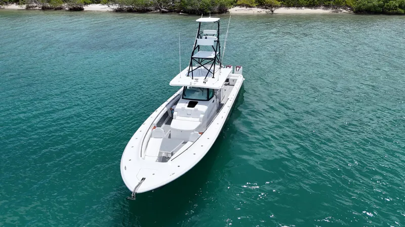  Yacht Photos Pics 2019 HCB 53 Sueños boat on clear turquoise water near a lush shoreline.