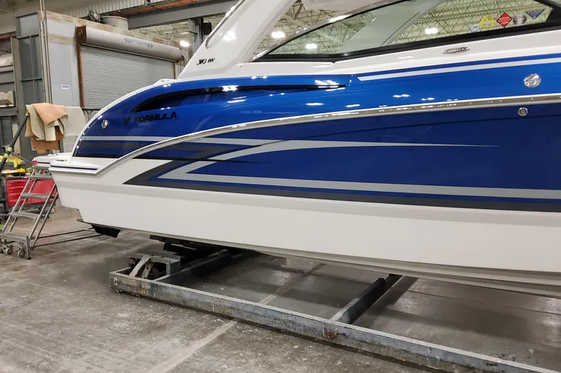  Yacht Photos Pics 2026 Formula 310 Bowrider I/O boat in a workshop, showcasing sleek blue and white design.