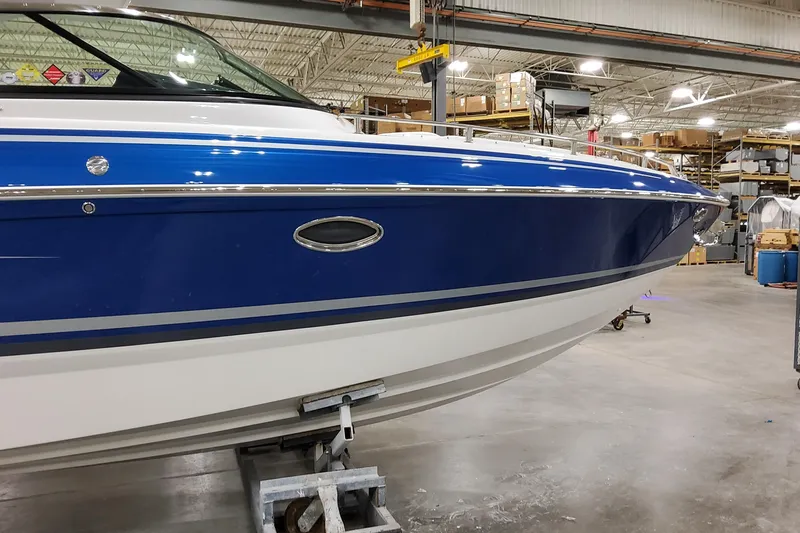  Yacht Photos Pics 2026 Formula 310 Bowrider I/O boat in a warehouse, showcasing sleek blue and white design.