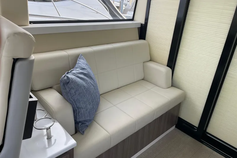 It's About Time Yacht Photos Pics Luxurious interior of 2022 Regal 38 Grande Coupe with cream leather seating and blue cushion.