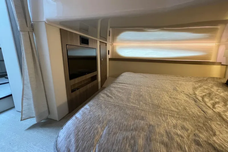It's About Time Yacht Photos Pics Luxurious interior of 2022 Regal 38 Grande Coupe with cozy bed and modern TV setup.