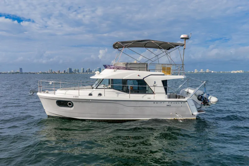  Yacht Photos Pics 2017 Beneteau Swift Trawler 30 on water with city skyline in background.