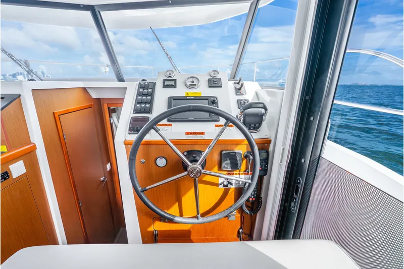  Yacht Photos Pics 2017 Beneteau Swift Trawler 30 helm with steering wheel and navigation controls.