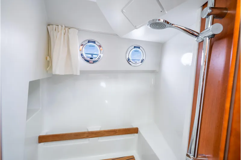  Yacht Photos Pics 2017 Beneteau Swift Trawler 30 bathroom with shower, portholes, and wooden accents.
