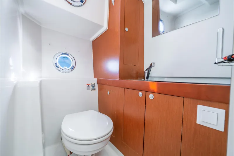  Yacht Photos Pics Bathroom interior of 2017 Beneteau Swift Trawler 30 with wooden cabinets and porthole.