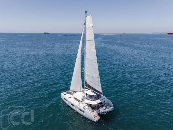Flying B Yacht Photos Pics 2021 Lagoon 46 catamaran sailing on open sea under clear blue sky.