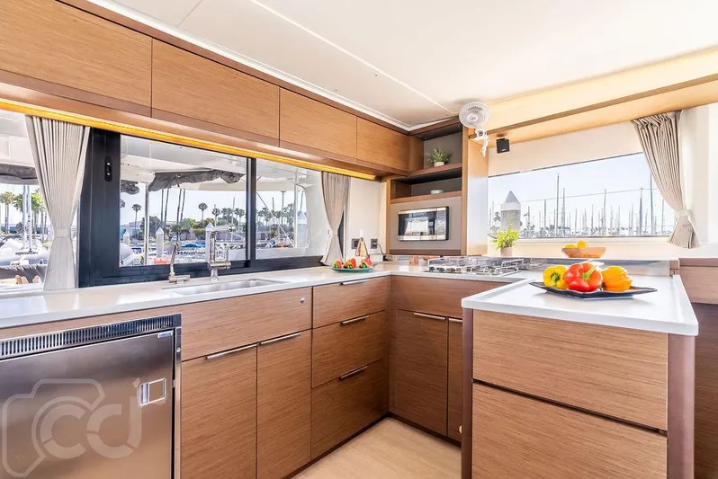Flying B Yacht Photos Pics Modern kitchen interior of 2021 Lagoon 46 yacht with wood cabinetry and marina view.