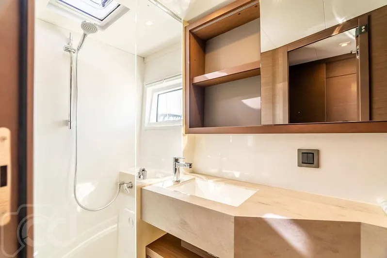 Flying B Yacht Photos Pics Modern bathroom in 2021 Lagoon 46 yacht with shower, sink, and wooden cabinetry.