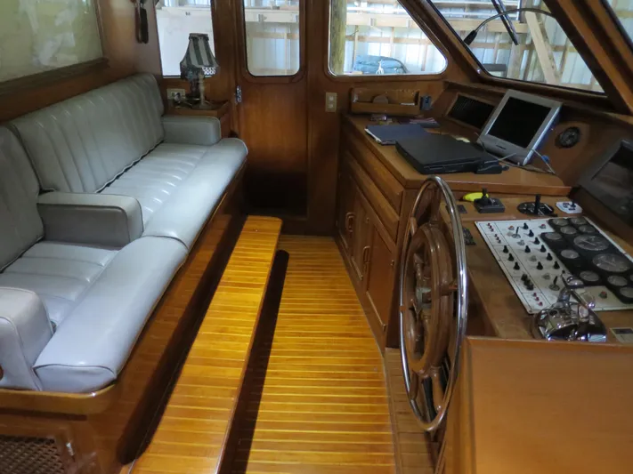 Water Doctor Yacht Photos Pics 1988 DeFever 53POC yacht interior with wooden helm, control panel, and cushioned seating.