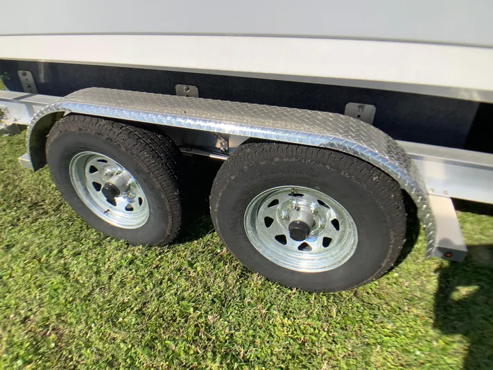 Highly Upgraded - 2025 Century 2600 Cc Yacht Photos Pics Trailer wheels of a 2025 Century 2600 Center Console boat on grass.