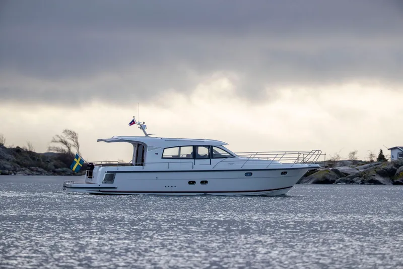  Yacht Photos Pics Nimbus 405 Coup&eacute; 2026 yacht cruising on a serene, cloudy waterway.