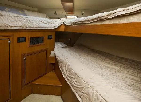 Motivator Yacht Photos Pics 1982 Pacifica Convertible interior with wooden bunk beds and cozy bedding.