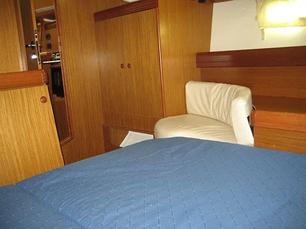 R Yacht Photos Pics Interior of 2006 Jeanneau Sun Odyssey 42 DS with wooden paneling and blue bedding.