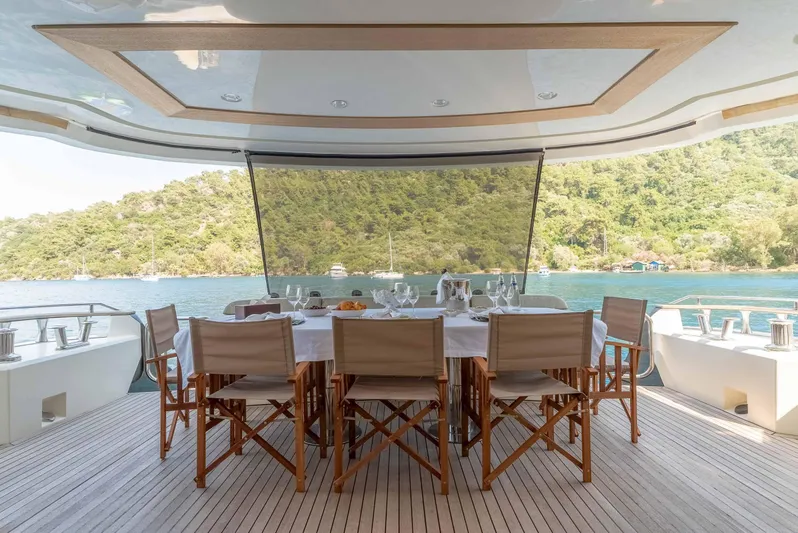  Yacht Photos Pics Luxurious dining area on 2016 Monte Carlo Yachts MCY 86, overlooking serene waters and lush greenery.
