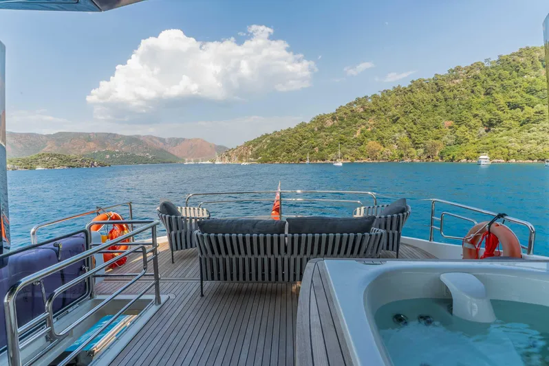  Yacht Photos Pics Luxurious Monte Carlo Yachts MCY 86 deck with jacuzzi, overlooking serene blue waters and lush hills.