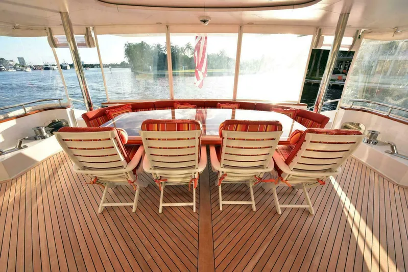 Waterford (name Reserved) Yacht Photos Pics Luxurious yacht deck with striped chairs, overlooking serene waters and palm trees.