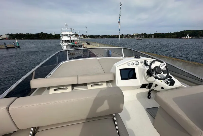  Yacht Photos Pics 2018 Cranchi E52F yacht helm with modern controls, docked by a scenic waterfront.