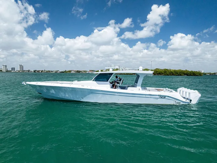  Yacht Photos Pics 2025 HCB 56' Sueños GIX luxury yacht cruising on clear blue water under a partly cloudy sky.
