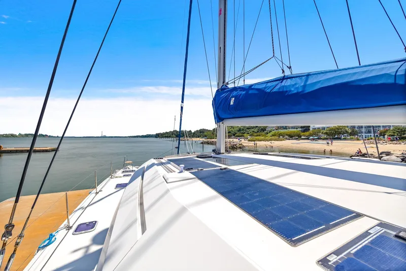 Vlaroda Yacht Photos Pics 2017 Nautitech 46 Open catamaran with solar panels, docked by a scenic shoreline.