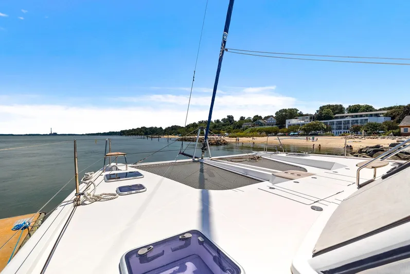 Vlaroda Yacht Photos Pics 2017 Nautitech 46 Open catamaran docked by a scenic shoreline under a clear blue sky.