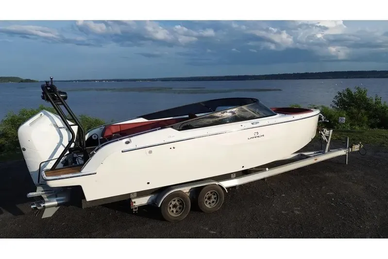  Yacht Photos Pics 2024 Cranchi E26 Classic boat on trailer by a lake under a cloudy sky.