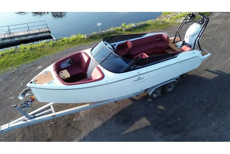  Yacht Photos Pics 2024 Cranchi E26 Classic boat on trailer by a lakeside.