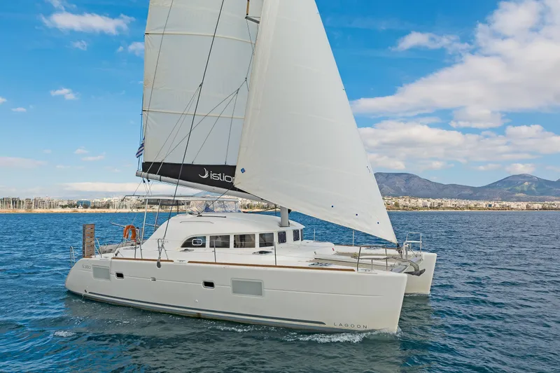  Yacht Photos Pics 2017 Lagoon 380 S2 catamaran sailing on blue ocean with mountains in background.