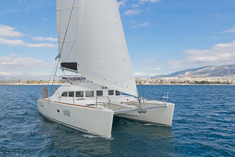  Yacht Photos Pics 2017 Lagoon 380 S2 catamaran sailing on blue ocean with cityscape and mountains in background.