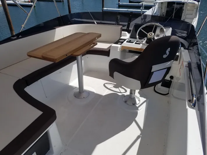  Yacht Photos Pics 2019 Beneteau Swift Trawler 35 cockpit with steering wheel, seating, and wooden table.