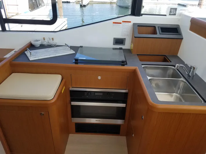  Yacht Photos Pics 2019 Beneteau Swift Trawler 35 kitchen with stove, sink, and wooden cabinetry.
