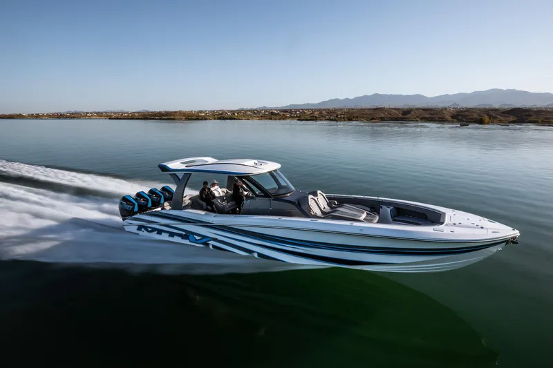  Yacht Photos Pics 2023 MTI V42 speedboat cruising on calm water with mountains in the background.
