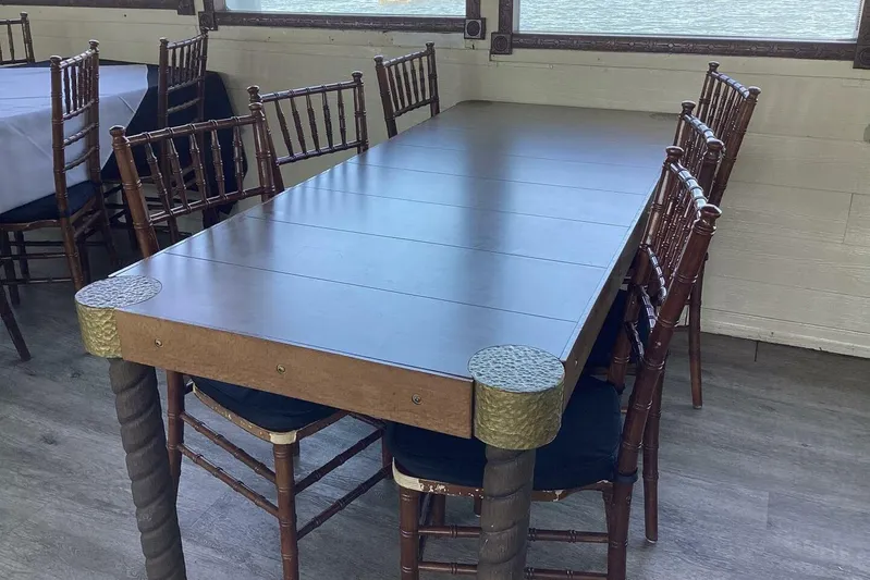 Indian River Queen Yacht Photos Pics Elegant dining setup with wooden chairs and a custom paddle wheel table, 1984 design.