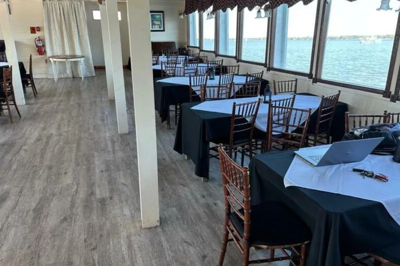 Indian River Queen Yacht Photos Pics Interior of a 1984 custom paddle wheel boat with tables, chairs, and a scenic water view.