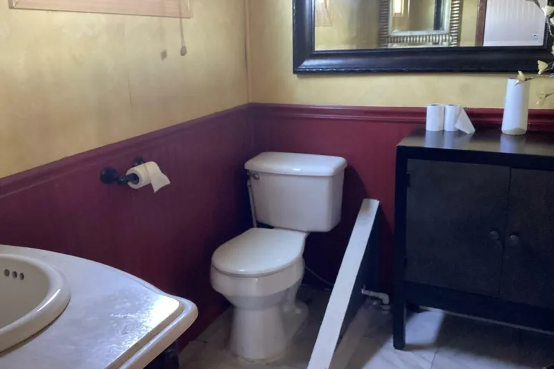 Indian River Queen Yacht Photos Pics Small bathroom with toilet, sink, mirror, and cabinet, featuring red and beige walls.