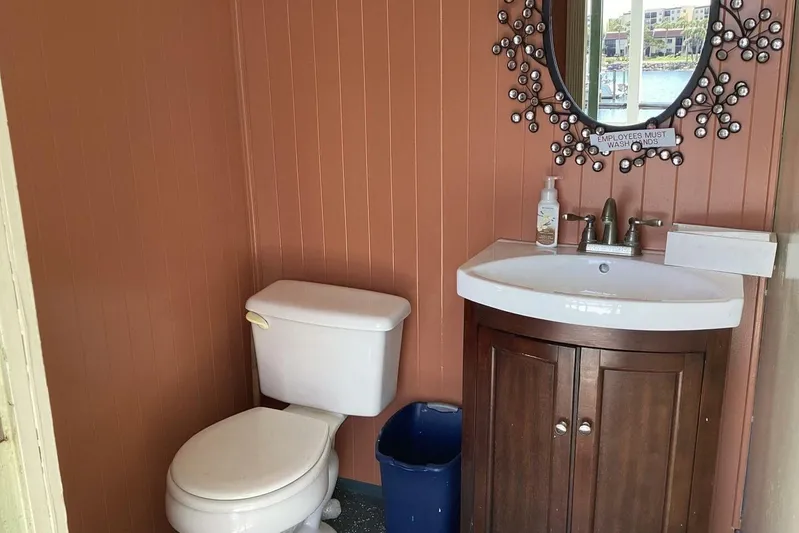 Indian River Queen Yacht Photos Pics Small bathroom with toilet, sink, decorative mirror, and "Employees Must Wash Hands" sign.