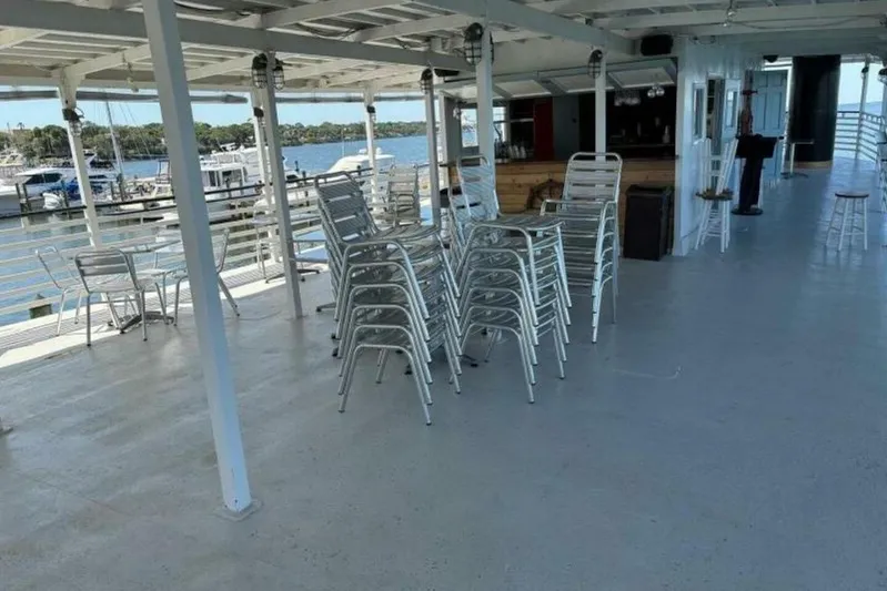 Indian River Queen Yacht Photos Pics Spacious deck of 1984 custom paddle wheel boat with stacked chairs and marina view.
