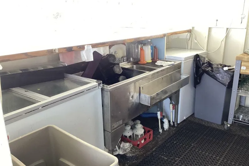 Indian River Queen Yacht Photos Pics Commercial kitchen sink area with storage, cleaning supplies, and equipment. Custom Paddle Wheel, 1984.